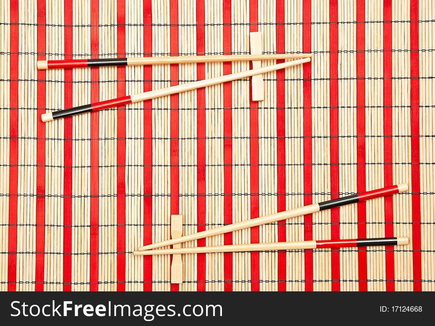 Red and black sticks for sushi on bamboo mat