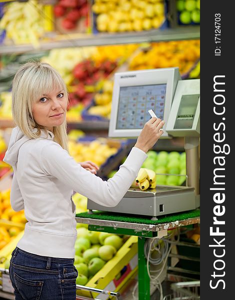 Beautiful young woman shopping for fruits and vegetables in produce department of a grocery store/supermarket