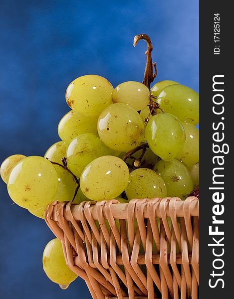 Green grapes in basket on a blue background