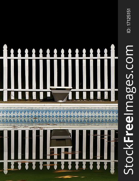A Swimming Pool and White Picket Fence at Night. A Swimming Pool and White Picket Fence at Night