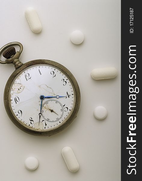 Old pocket watch surrounded by pills. Old pocket watch surrounded by pills