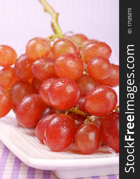 Red Sultana grape on a white plate. Studio shot. Selective focus, shallow DOF. Red Sultana grape on a white plate. Studio shot. Selective focus, shallow DOF.