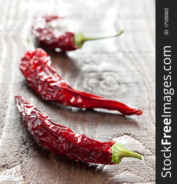 Three dried chili pepper on wooden table