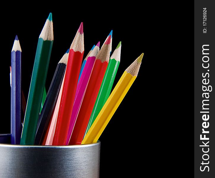 Holder full of colorful pencils isolated on black background