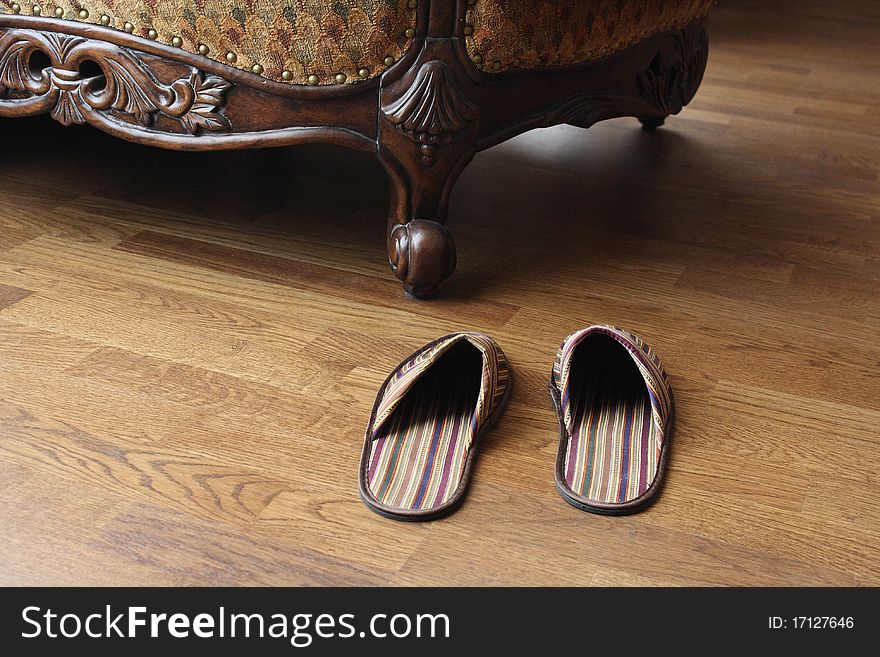 The slippers which are standing near an armchair.