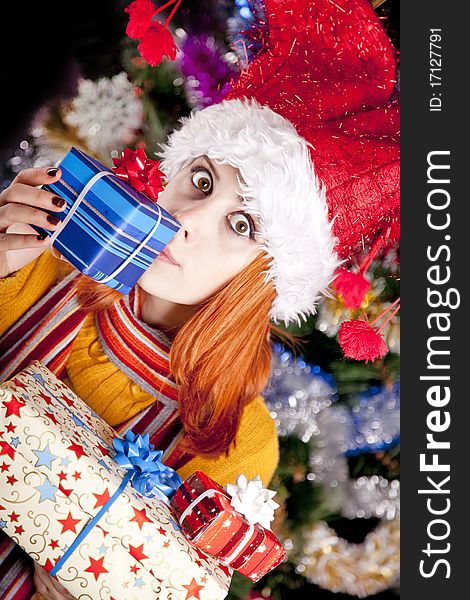 Funny girl in christmas cap with gift boxes