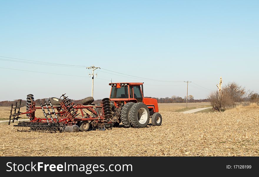 Red farm tractor with a plow in a field. Red farm tractor with a plow in a field