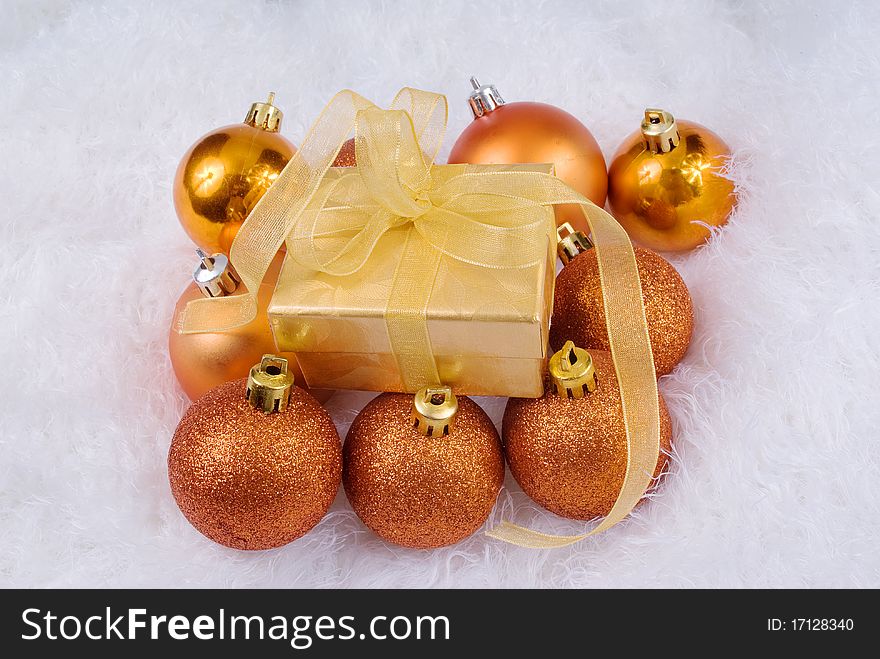 Christmas spheres and golden box on the white fur