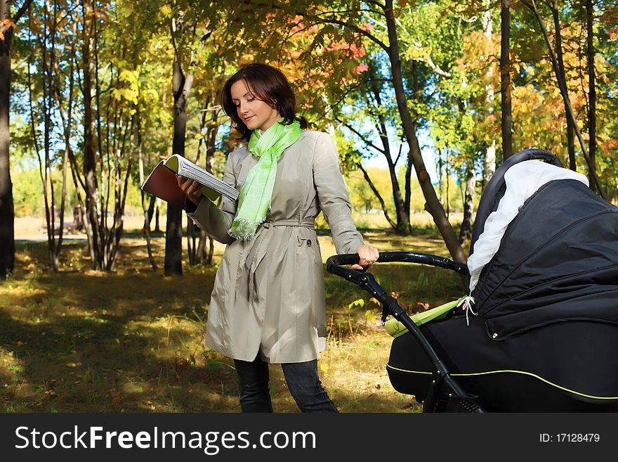 Happy mother walking at the autumn park with her baby.