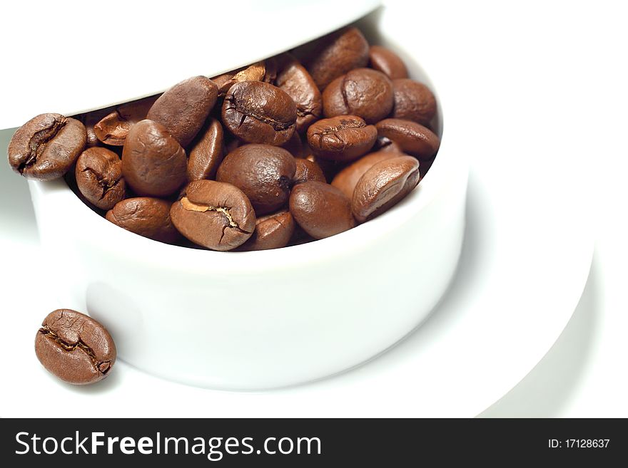 Coffee beans in a white porcelain cup. Coffee beans in a white porcelain cup.