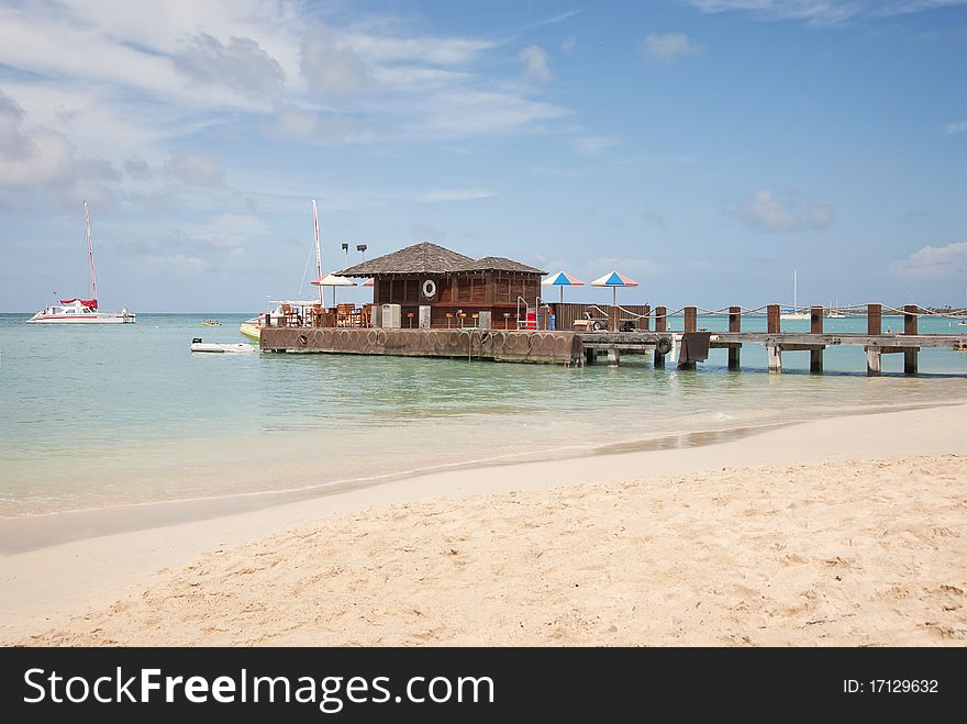 A beach bar built on a pier with the beach in the foreground. A beach bar built on a pier with the beach in the foreground.