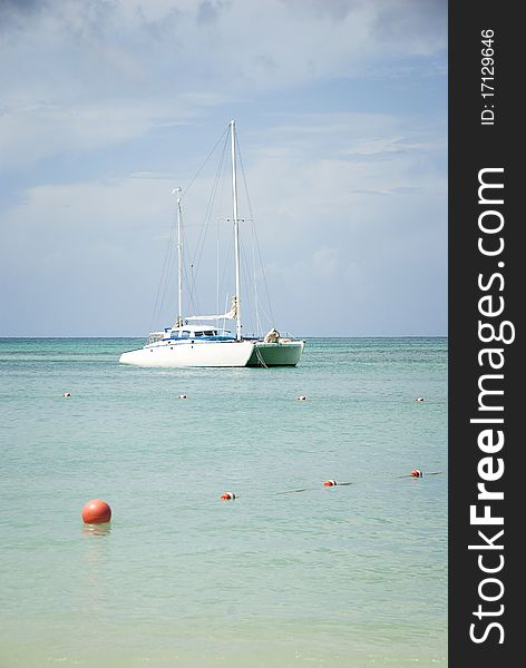 A white catamaran sailboat anchored off shore in the Caribbean.