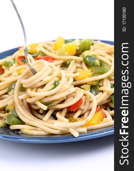 Spaghetti with vegetables being eaten with a fork on white background