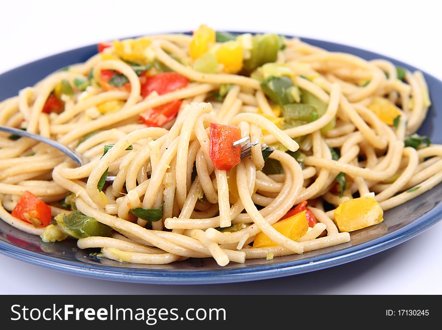 Spaghetti with vegetables with a fork on white background