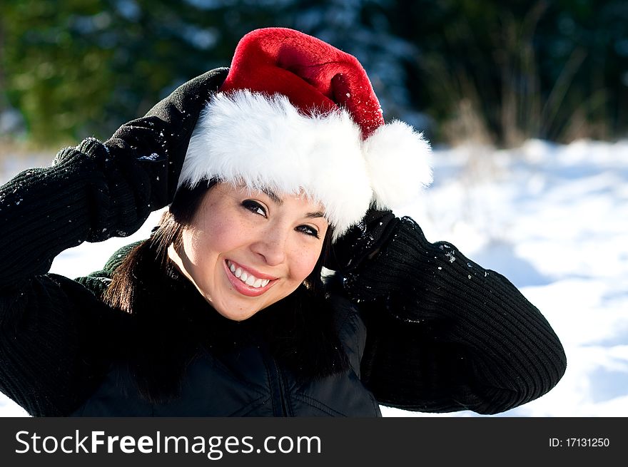 Cute young woman in the snow wearing Santa hat. Cute young woman in the snow wearing Santa hat