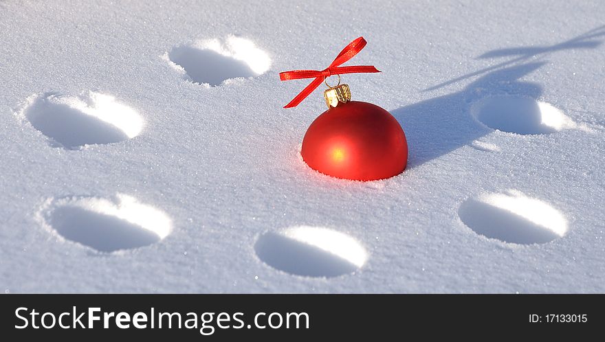 A red Christmas bauble sitting in a bed of snow. A red Christmas bauble sitting in a bed of snow