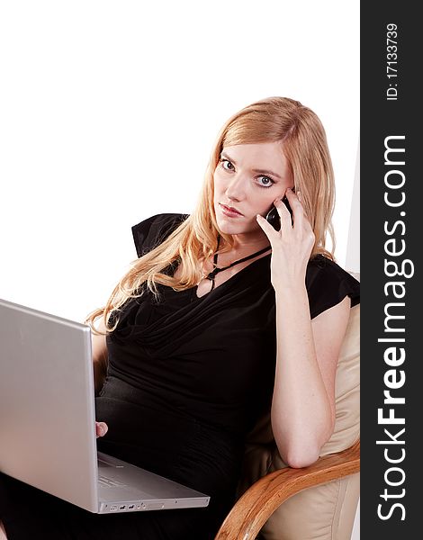 A business woman listening to a call on her cell while she is working on her laptop. A business woman listening to a call on her cell while she is working on her laptop.