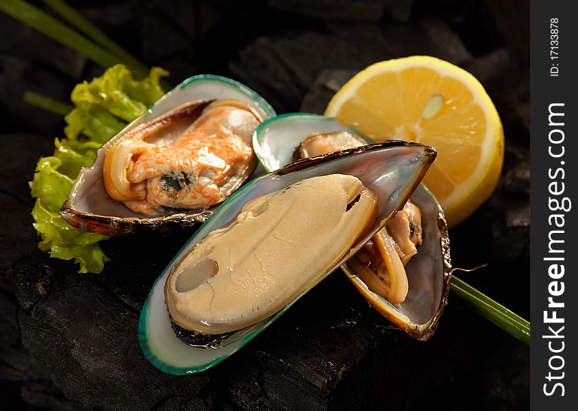 Mussels with salad and lemon on carbons