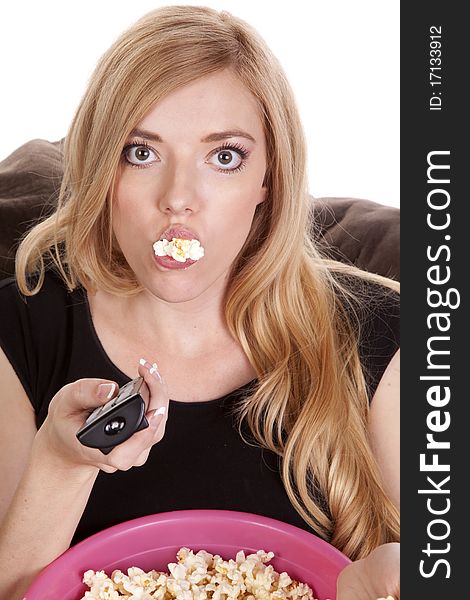 A woman sitting on a bean bag while she is enjoying her popcorn with it falling out of her mouth. A woman sitting on a bean bag while she is enjoying her popcorn with it falling out of her mouth.