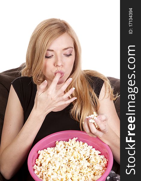 A woman sitting on a bean bag while she is enjoying her popcorn. A woman sitting on a bean bag while she is enjoying her popcorn.