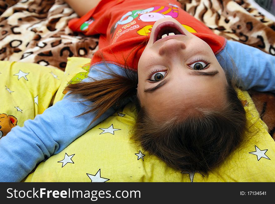 Happy, the little girl lies on a bed on a back having stretched hands. Happy, the little girl lies on a bed on a back having stretched hands