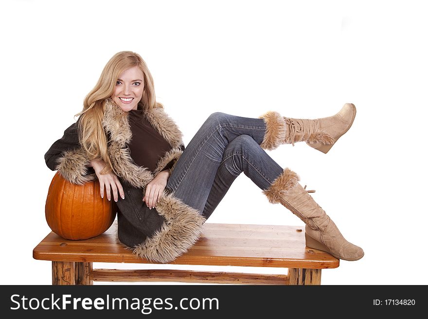 A woman laying on a pumpkin in her warm fuzzy boots and coat. A woman laying on a pumpkin in her warm fuzzy boots and coat.