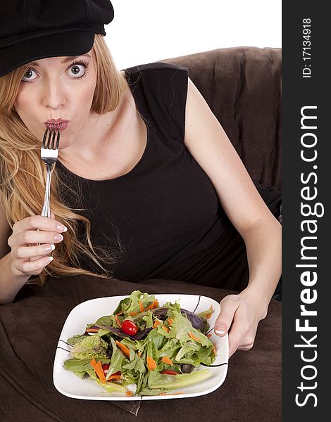 A woman sitting on a bean bag while she is enjoying her nice green salad. A woman sitting on a bean bag while she is enjoying her nice green salad.