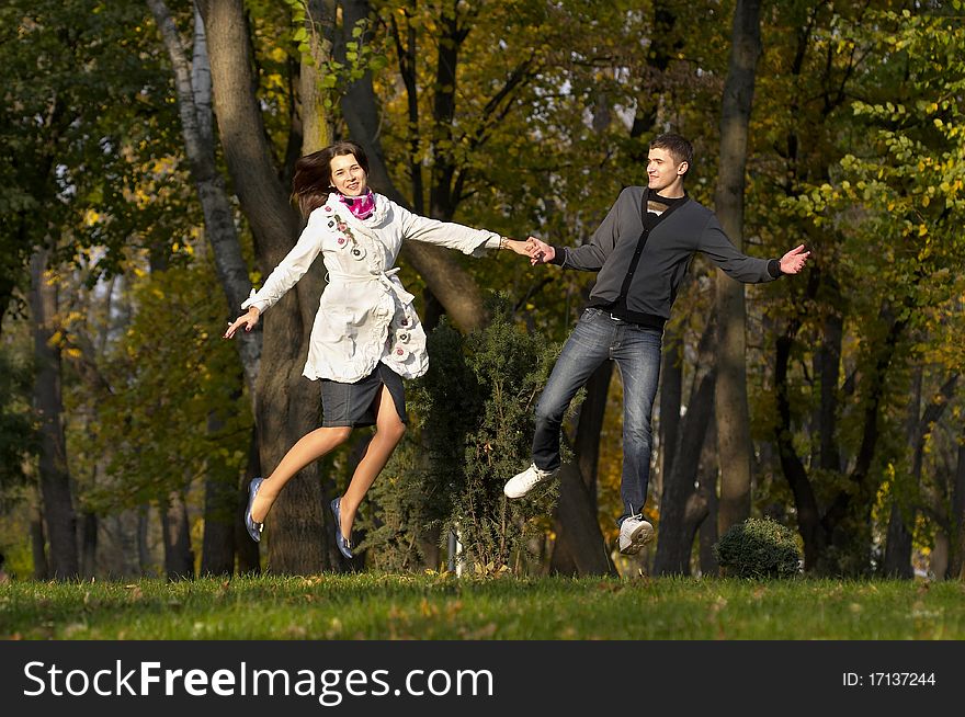 Young couple jumping in autumn park over defocused background. Young couple jumping in autumn park over defocused background