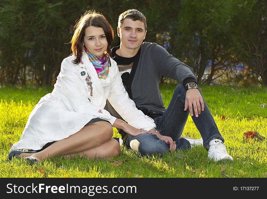 Young couple sitting in the autumn city park (defocused background). Young couple sitting in the autumn city park (defocused background)