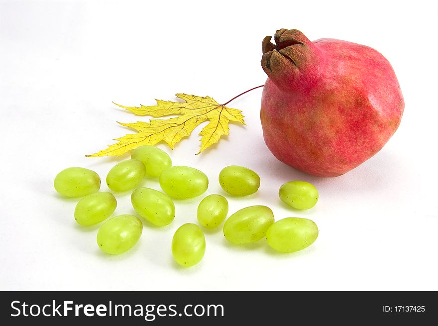 Pomegranate, grapes and maple-leaf on a white background