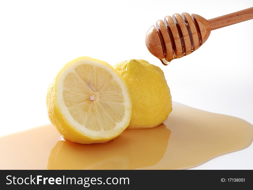 Honey dripping on a lemon slice isolated on white. Honey dripping on a lemon slice isolated on white.