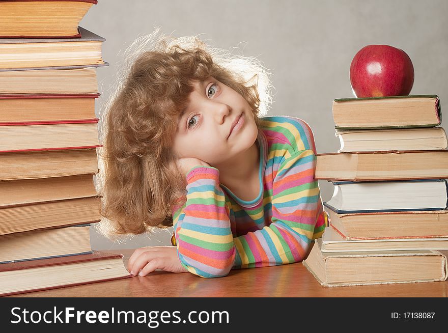 Little girl with pile of books and apple.