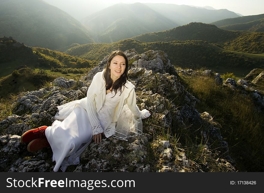 Romantic woman with red boots sitting on rocks