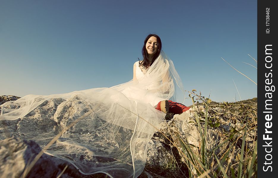 Romantic woman with red boots sitting on rocks