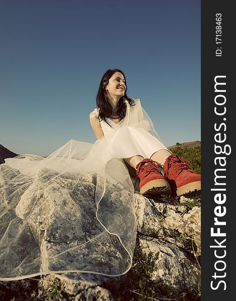 Romantic woman with red boots sitting on rocks