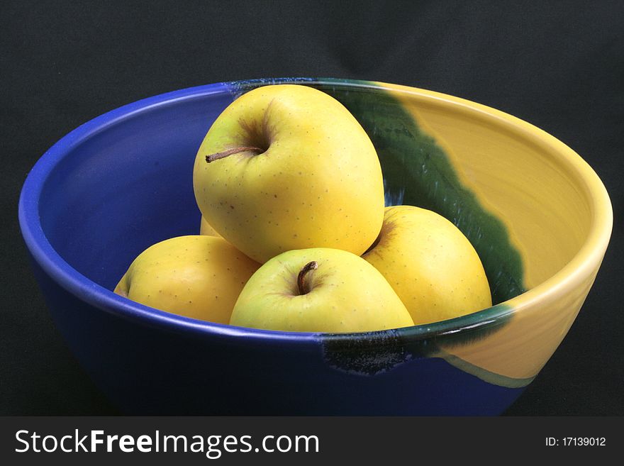 Basket of yellow apples on a black background