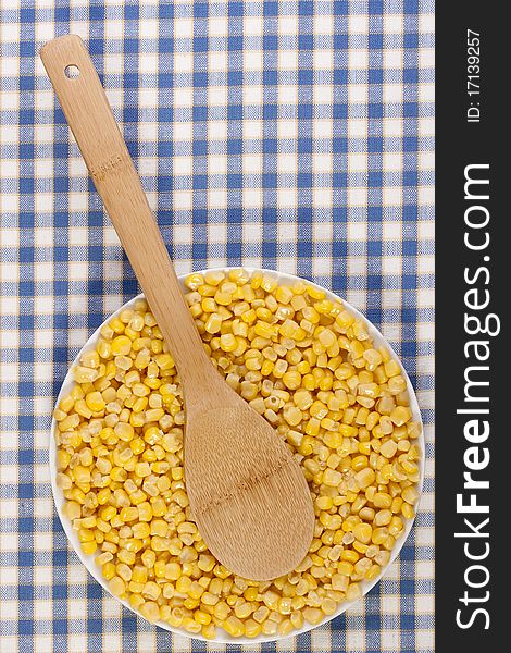 Canned corn in a white plate against the checkered background.