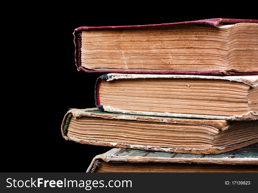 A few old books stacked in a pile on a black background