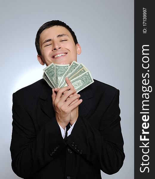 Expressions - Young handsome business man in black suit and tie counting money. gray background. Expressions - Young handsome business man in black suit and tie counting money. gray background