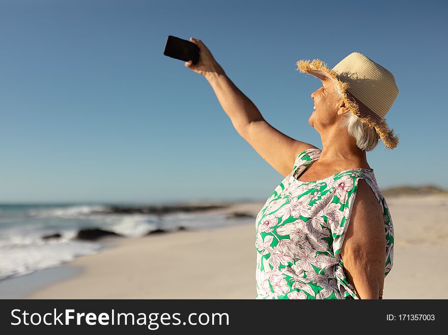 Old woman taking selfies at the beach