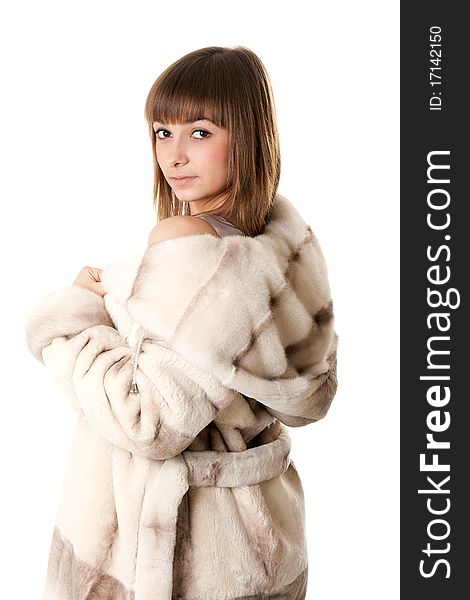 A beautiful young girl in a fur coat on a white background