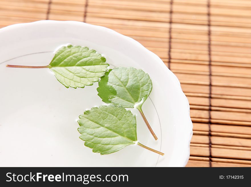 Leaves decorating a white plate on a bamboo sticks table