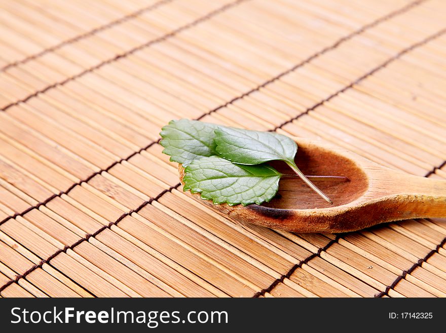 Leaves decorating a wooden spoon on a bamboo sticks table