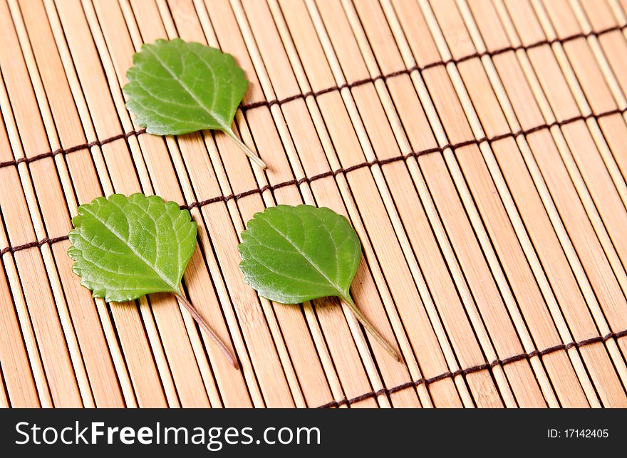 Three leaves on a bamboo sticks table. Background