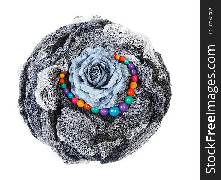 Varicoloured scarf is put with necklace around and flower on white background