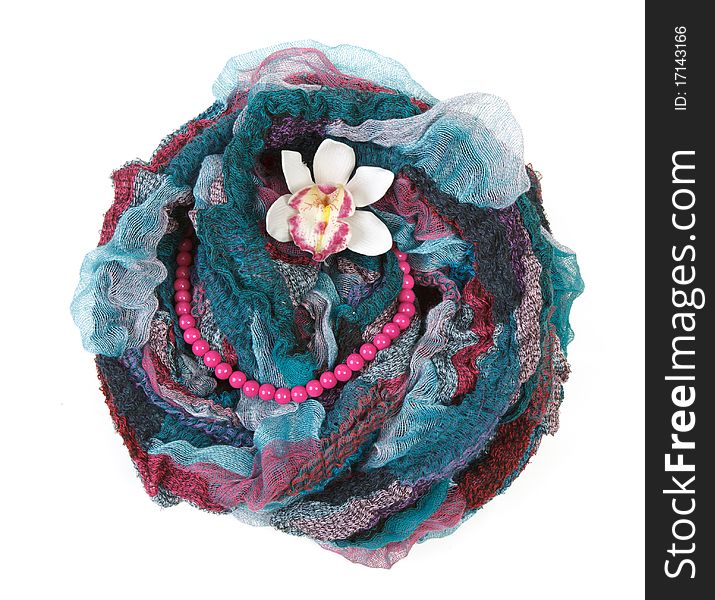 Varicoloured scarf is put with necklace around and flower on white background