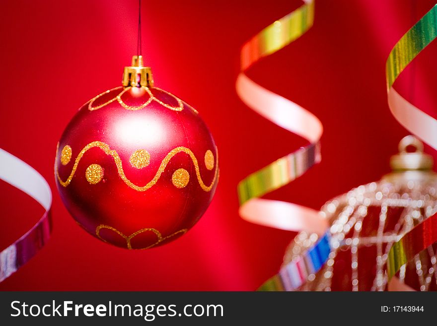 Red christmas ball and golden tinsel hang. Red background