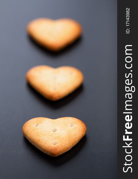 Three salted heart shaped crackers on black background. Three salted heart shaped crackers on black background