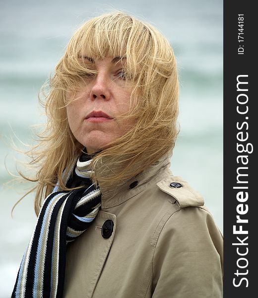 Mid-aged blonde lady staying on sea shore autumn. Mid-aged blonde lady staying on sea shore autumn