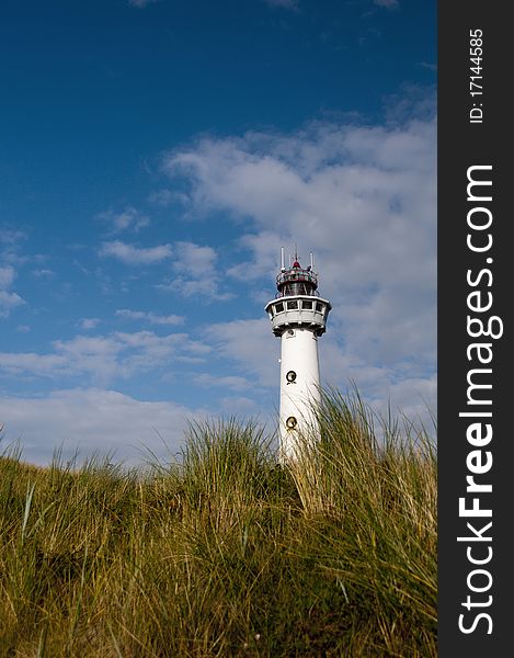 A lighthouse on top of a dune with blue sky background in Holland